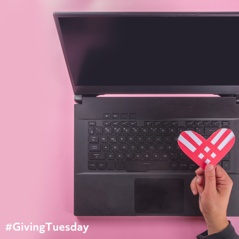 Laptop computer with a hand holding a Giving Tuesday logo heart.